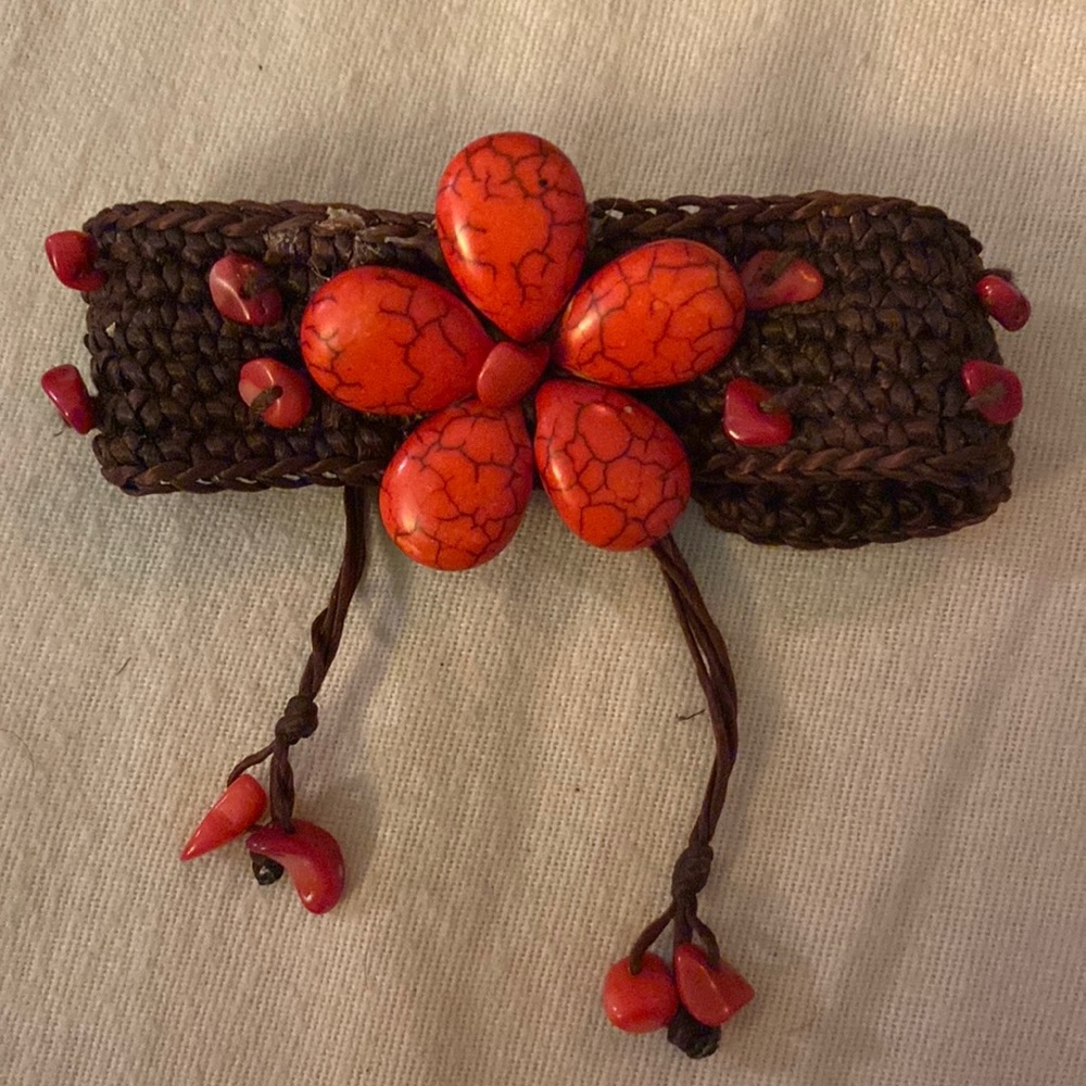 Adjustable woven bracelet with red stones creating a flower and stones woven in